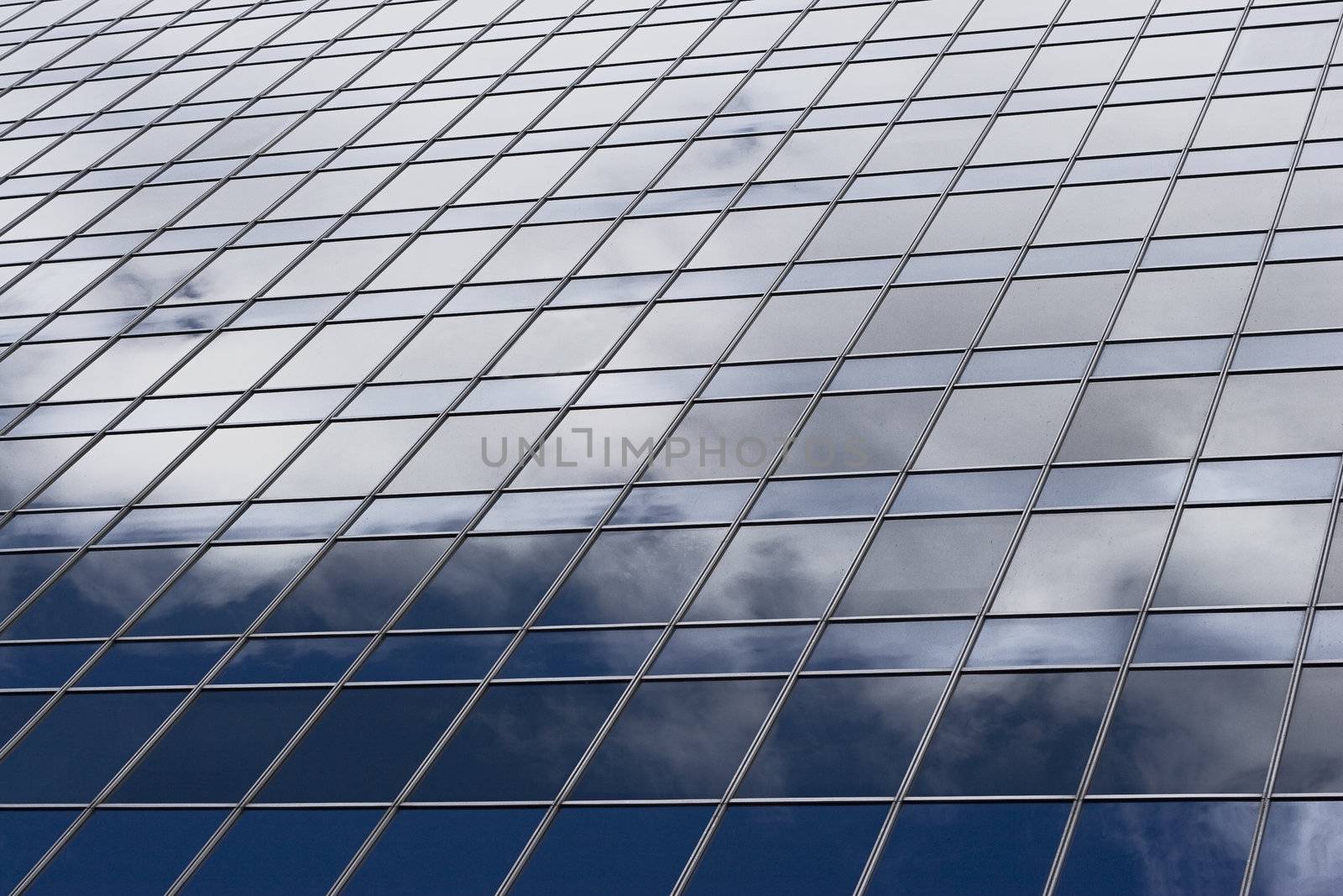 close up of skycraper window reflecting a blue sky and clouds