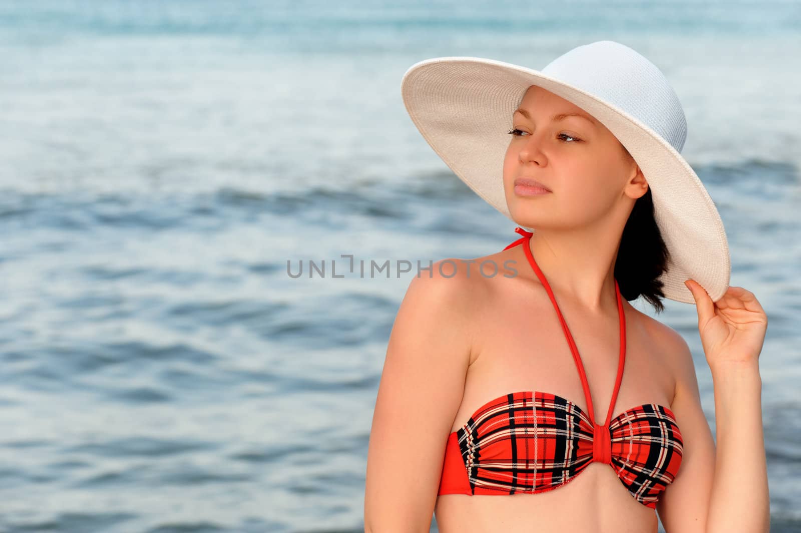 The girl in a hat against the sea and blue sky