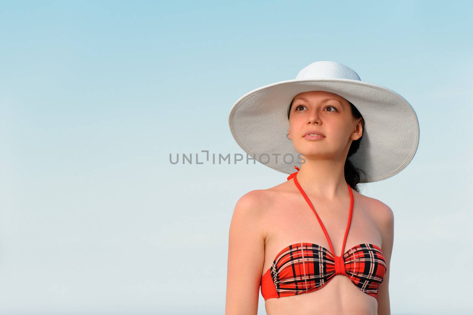 The girl in a hat against the blue sky