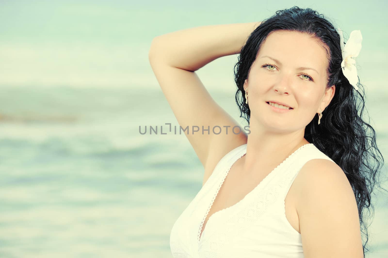 The woman in a white sundress on seacoast. Warm toned image