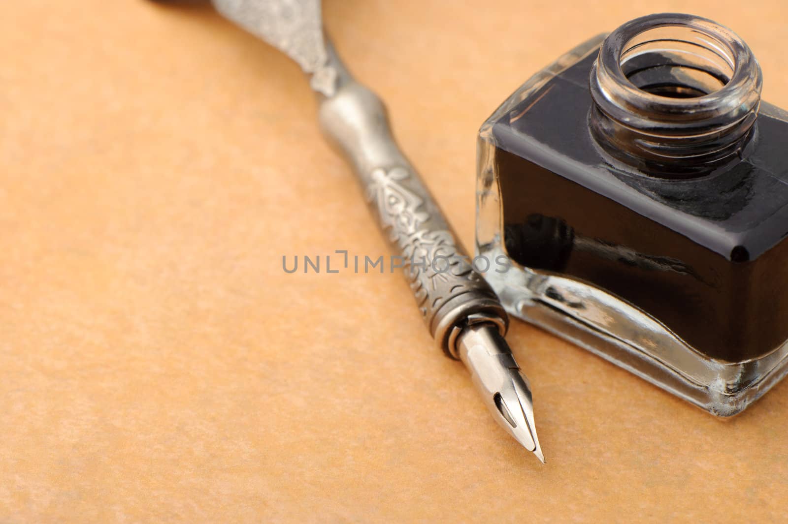 Feather quill and inkwell on an old paper. Photo closeup