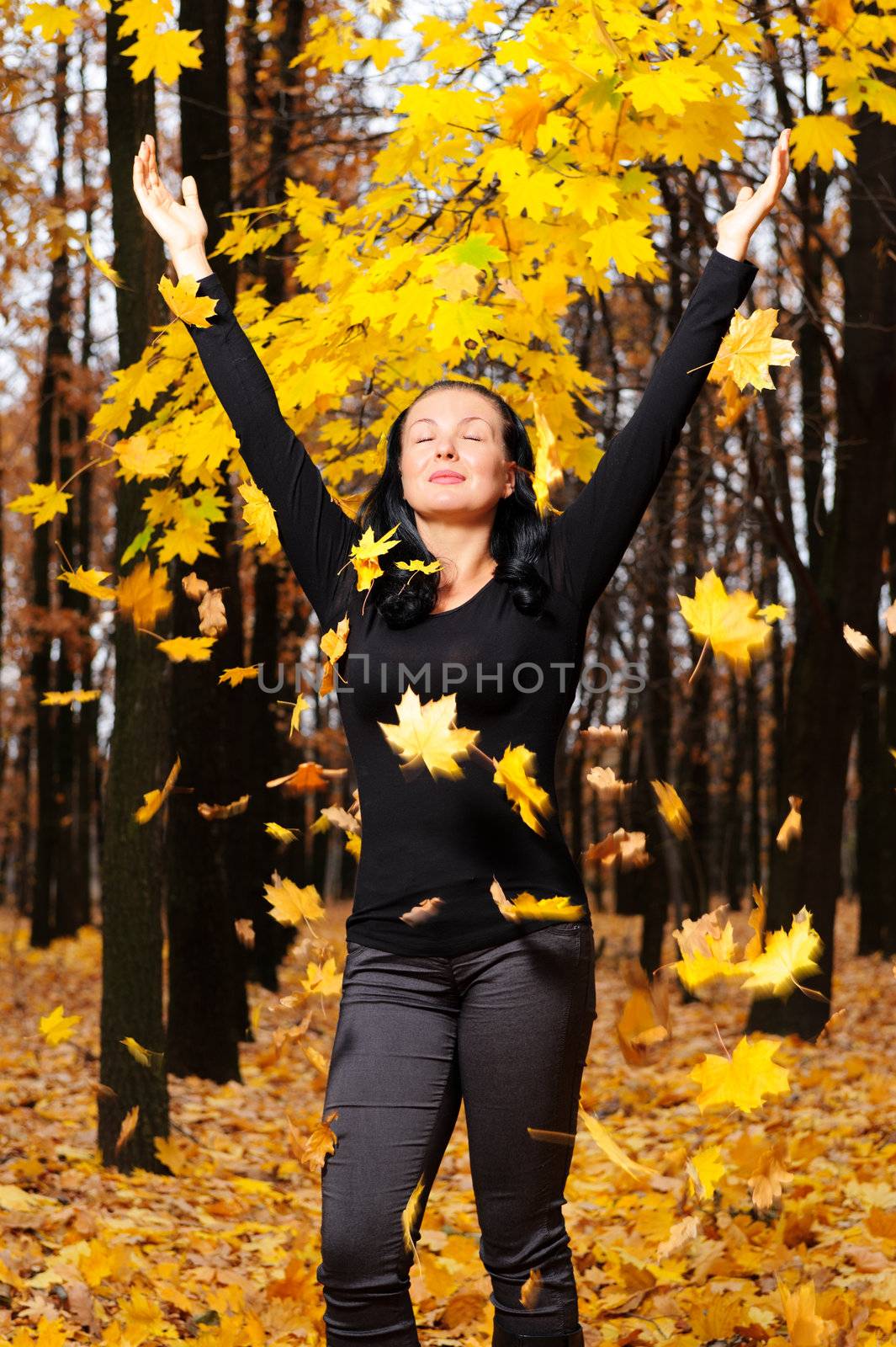 The women with the lifted hands autumn forest. Falling yellow leaf
