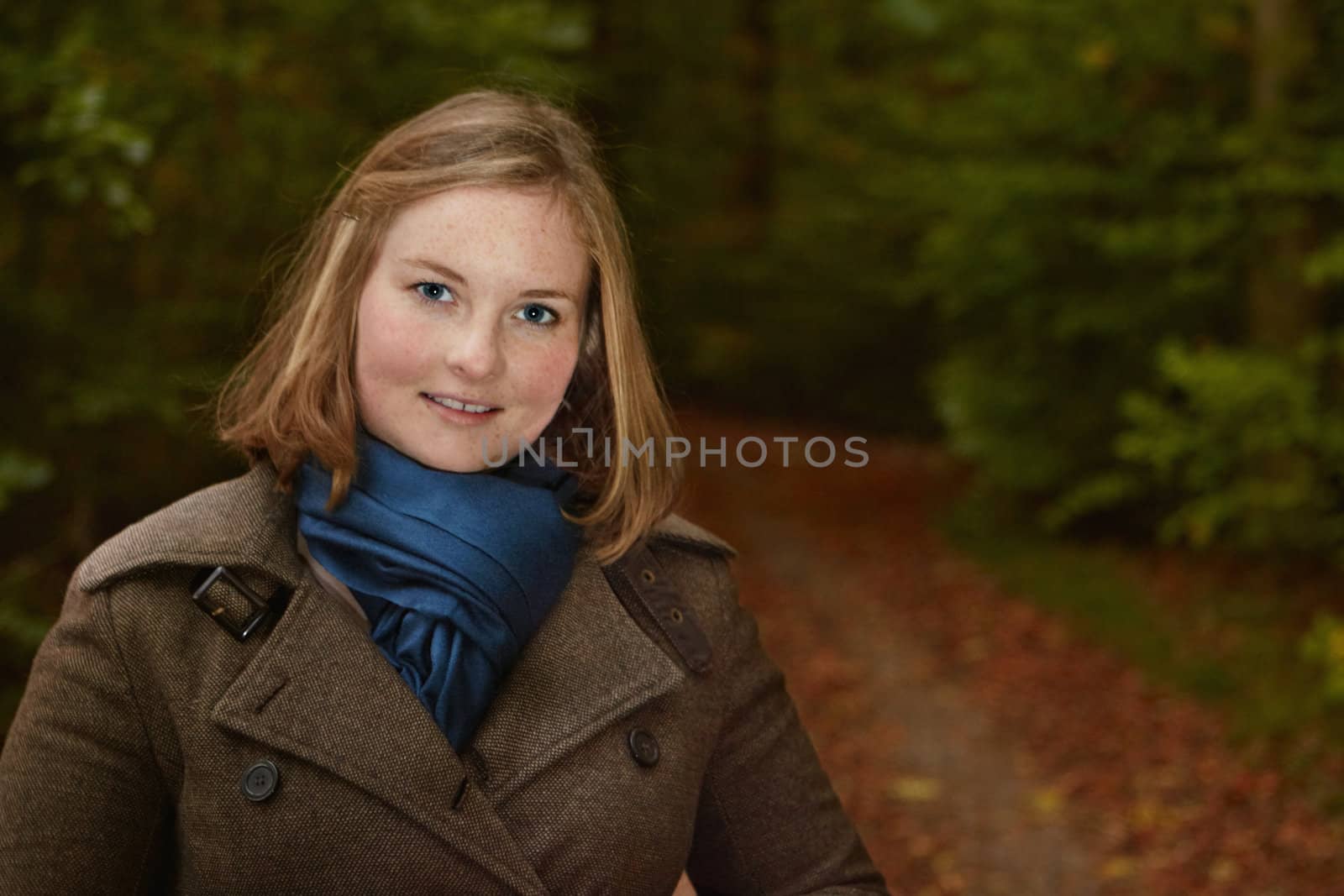 Freindly young woman standing by a  path in the forest