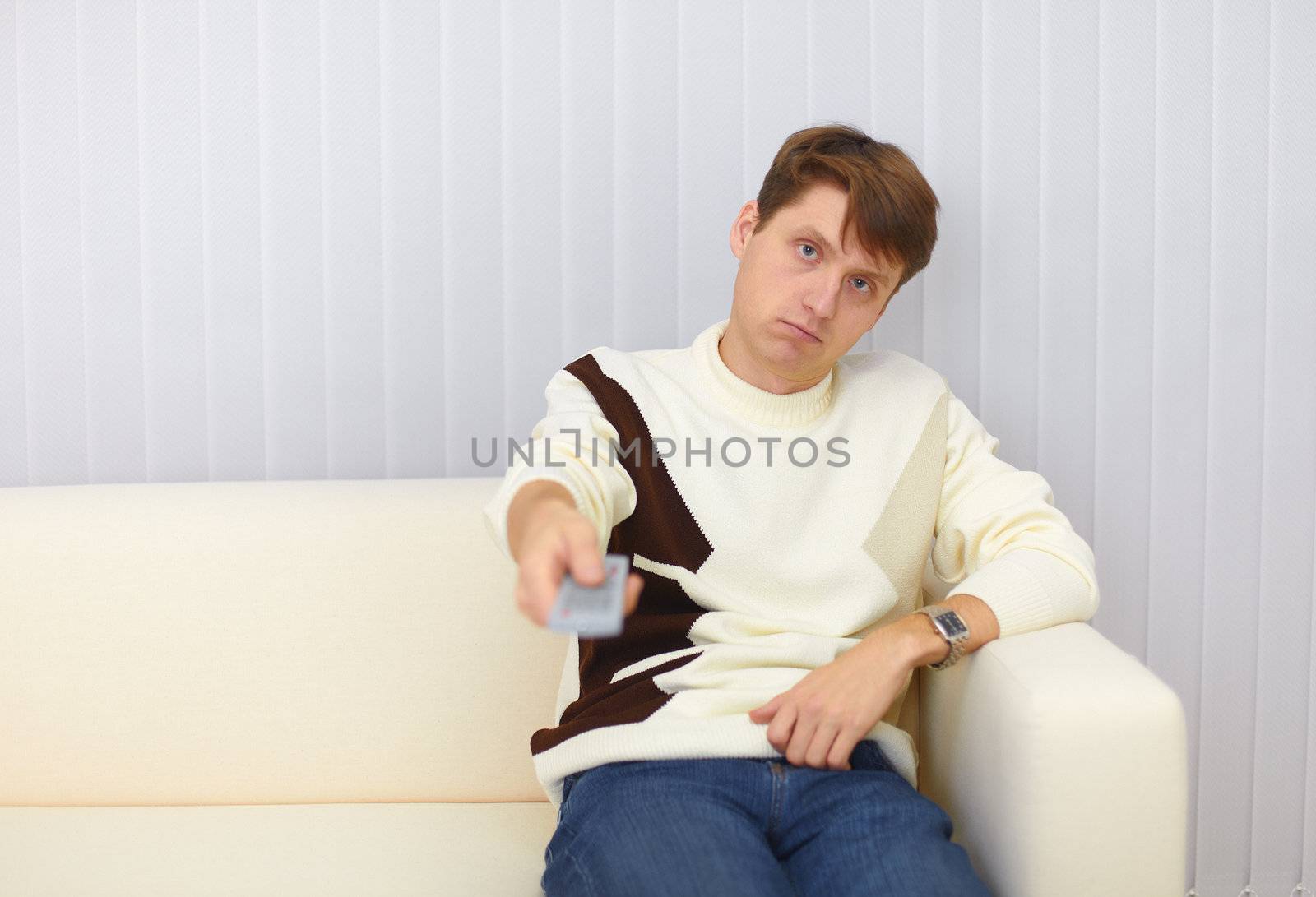 The guy sits on a sofa and watches TV