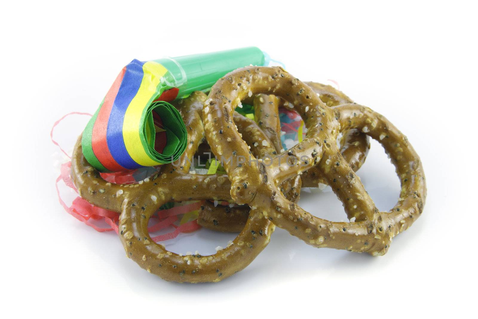 Two salty baked pretzels with party streamers and party blower on a reflective white background