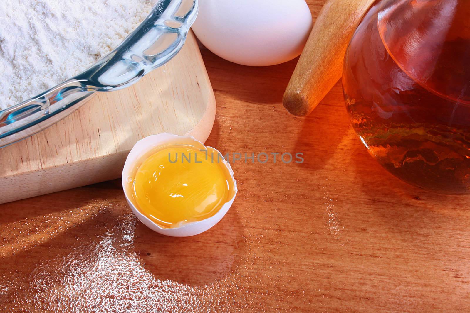 The forms prepared for a batch, and also components: a flour, eggs, oil, on a chopping board with Rolling pin.