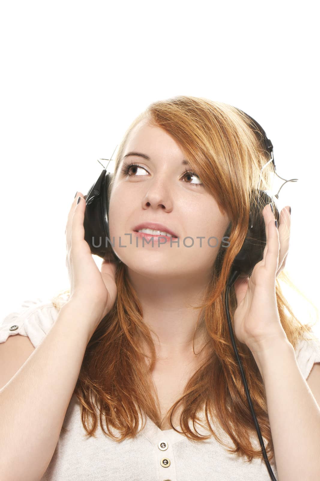 young redhead woman is daydreaming while listening to music with headphones by RobStark