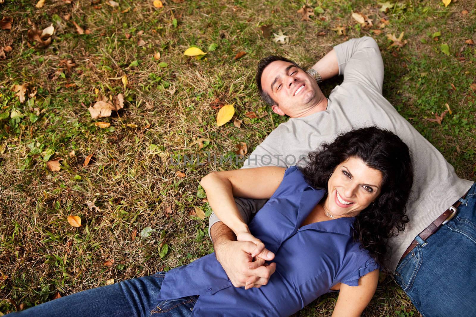 A happy couple daydreaming in a park on grass - sharp focus on woman
