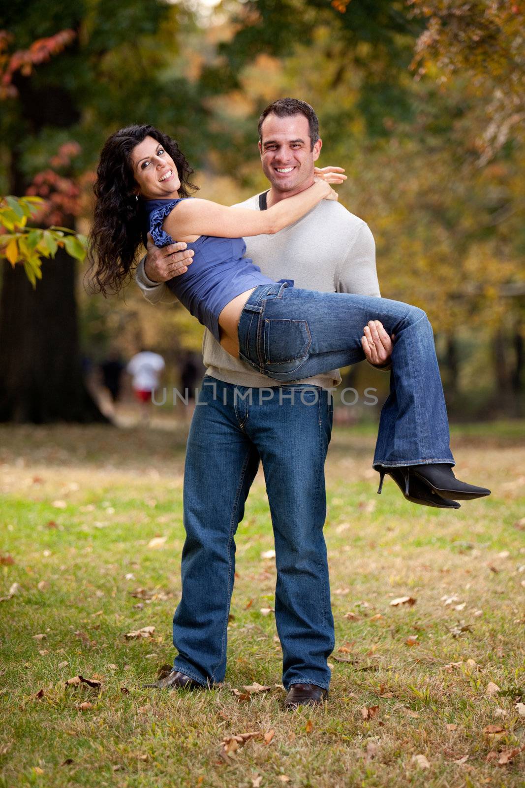 A happy healthy couple in the park - Man holding the Woman