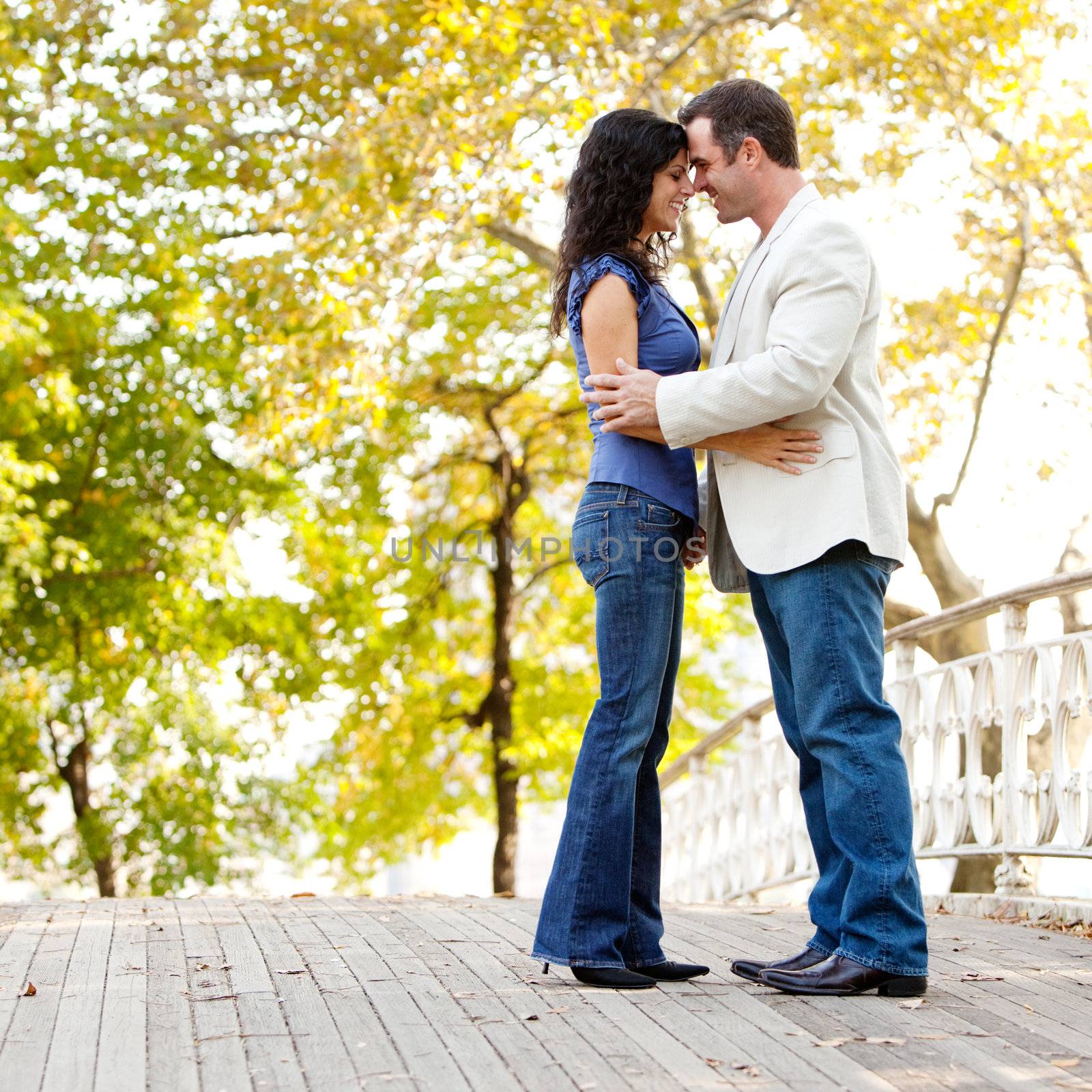 A happy couple in the park looking at the camera and hugging