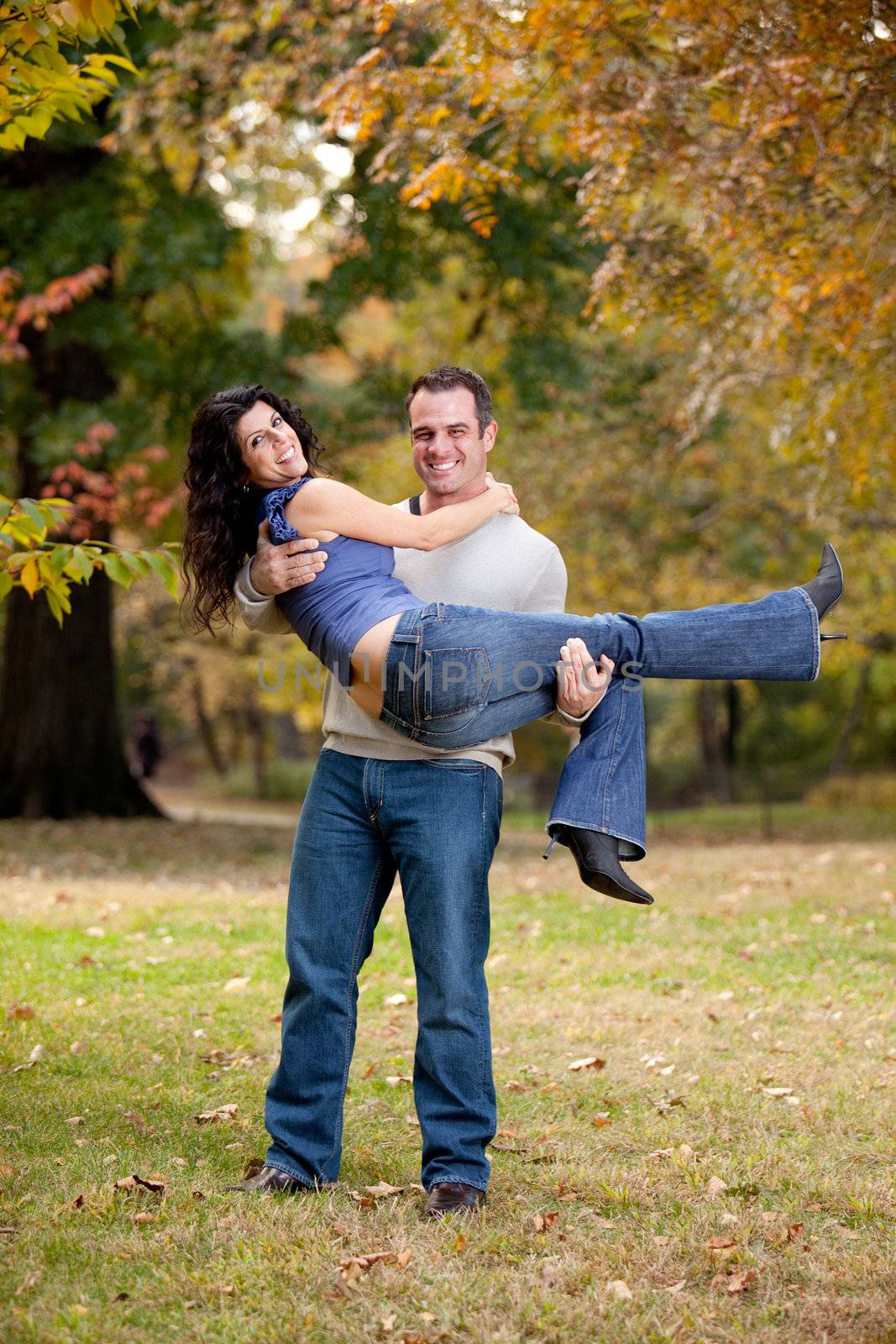 A happy healthy couple in the park - Man holding the Woman