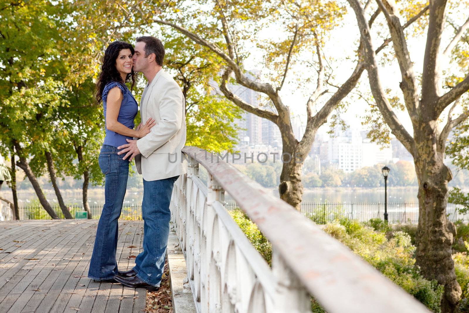 A man kissing a woman in a park on a bridge