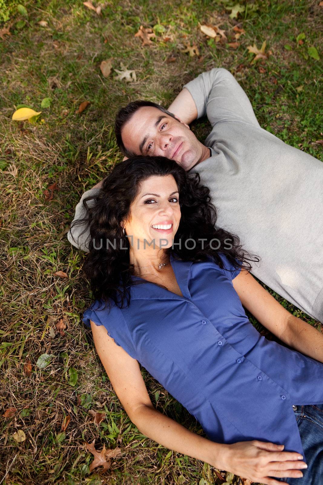 A couple in the park laying on the grass.  Sharp focus on female.