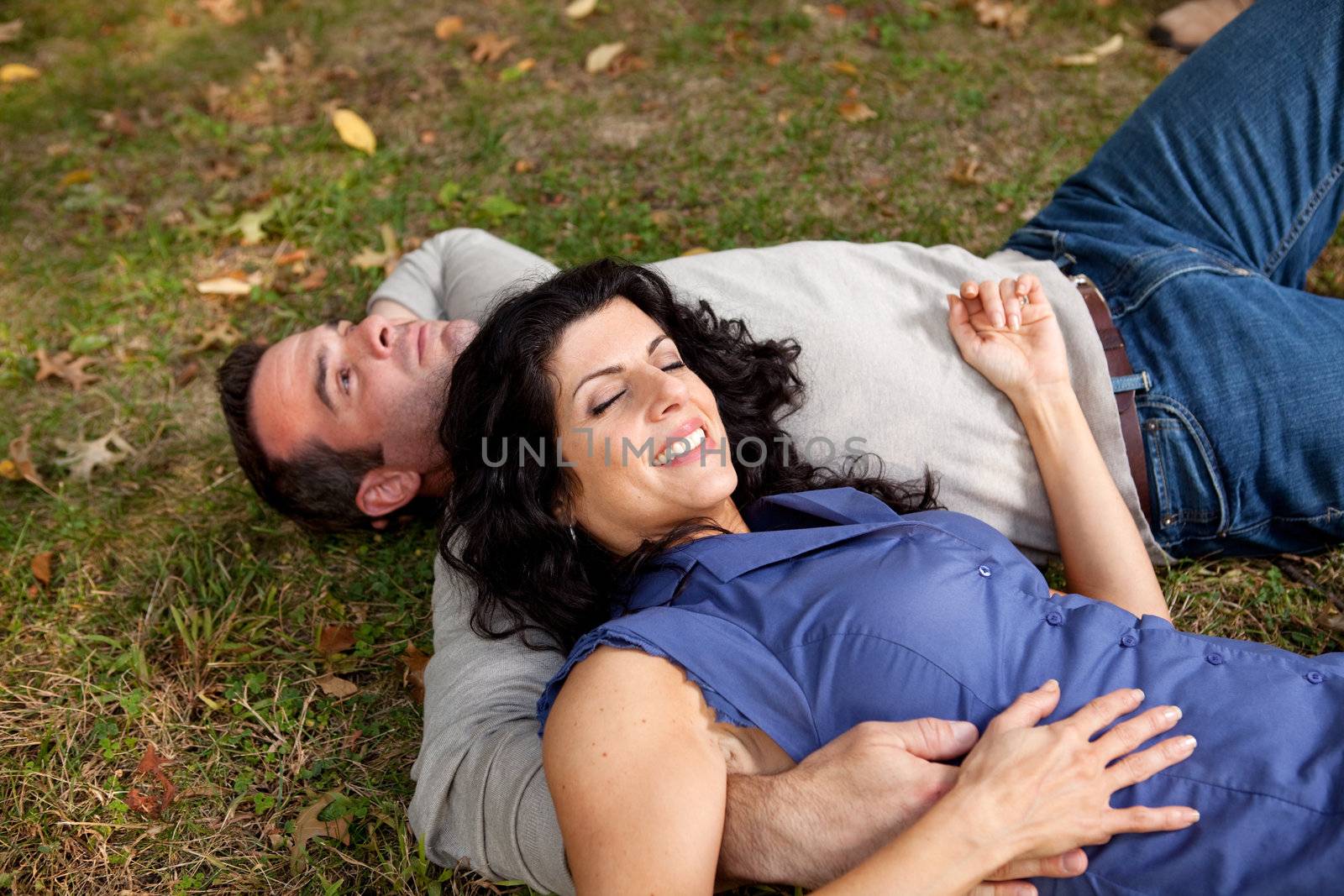 A couple laying on grass in a park