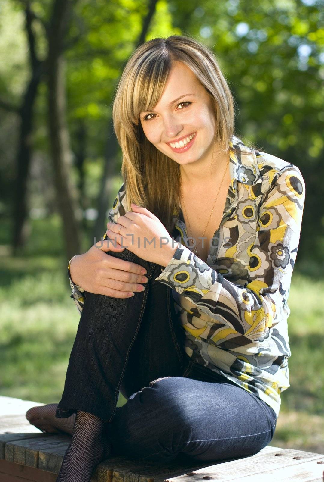 A young blond girl relaxing outdooers in a park in a warm sunny day