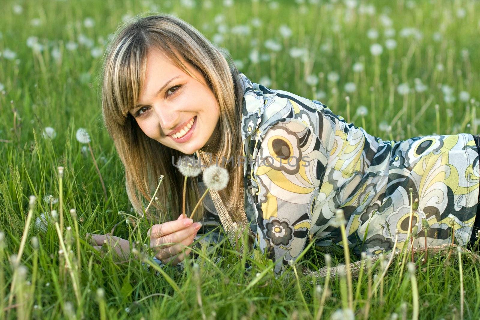 A young blond girl relaxing outdooers on a meadow in a warm sunny day