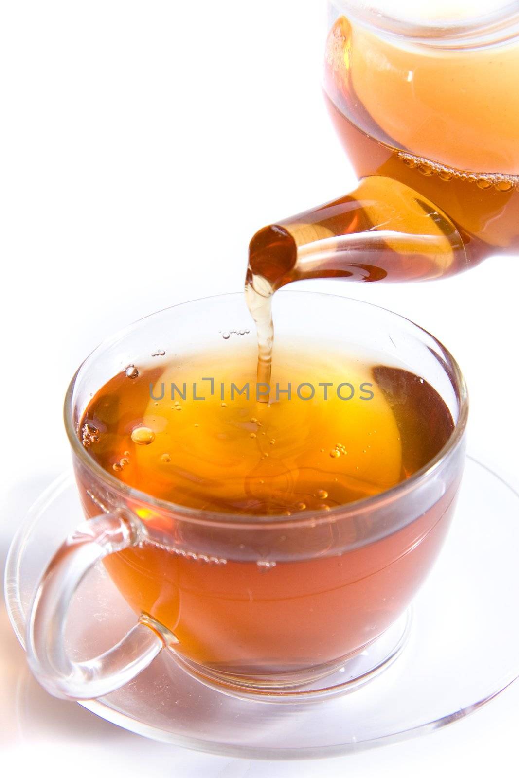 Pouring tea to a transparent teacup on white background