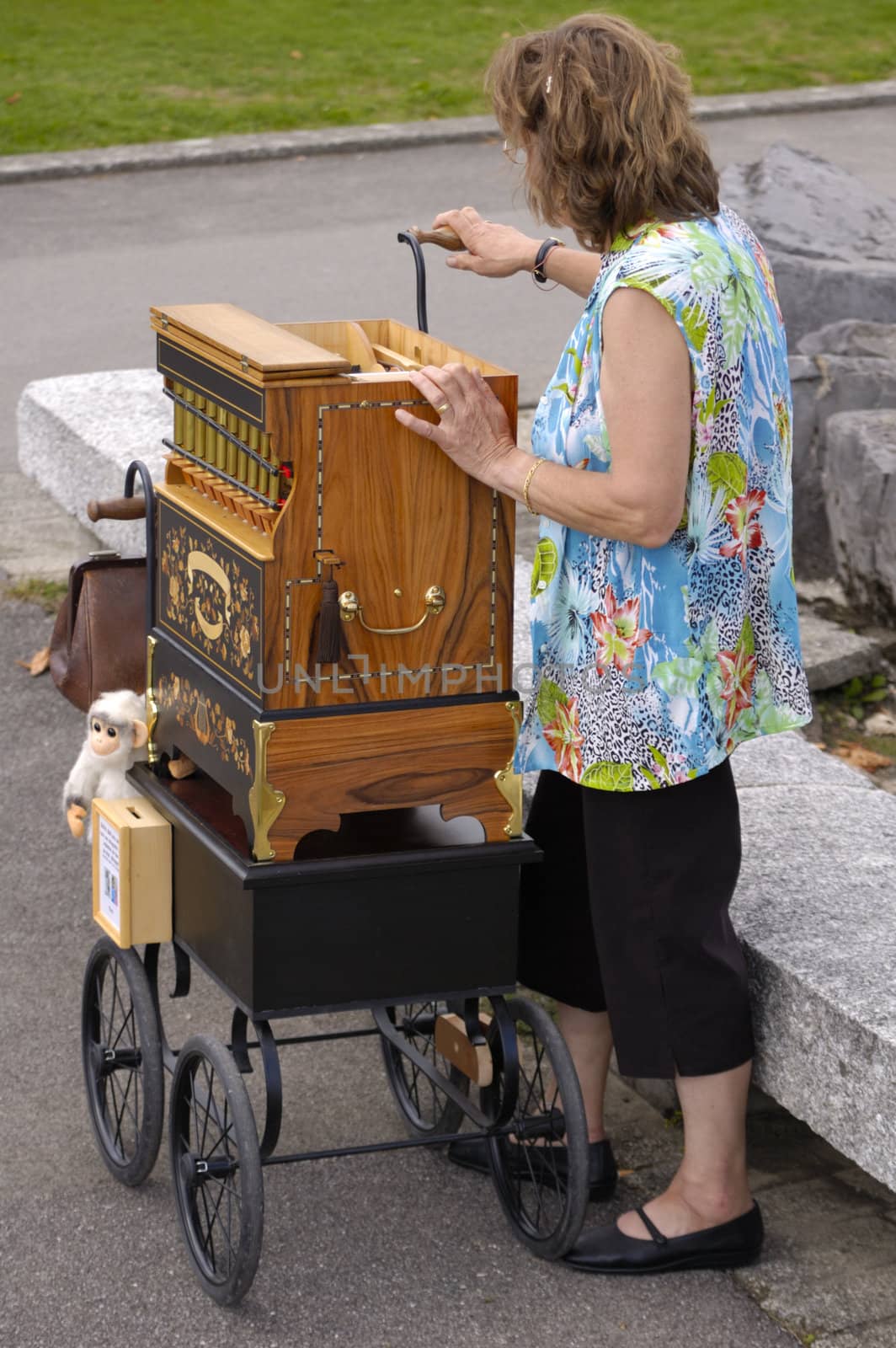 A woman barrel organ player, complete with monkey, playing her music to an empty street.