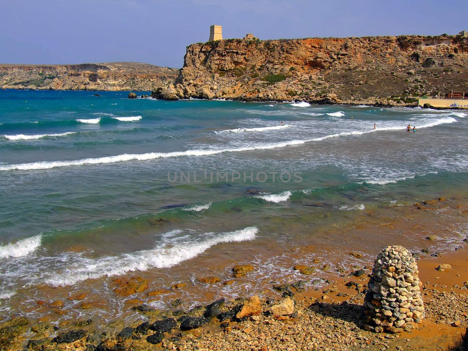 Clear blue Mediterranean waters on windy day, with beach and typical rocky coastline