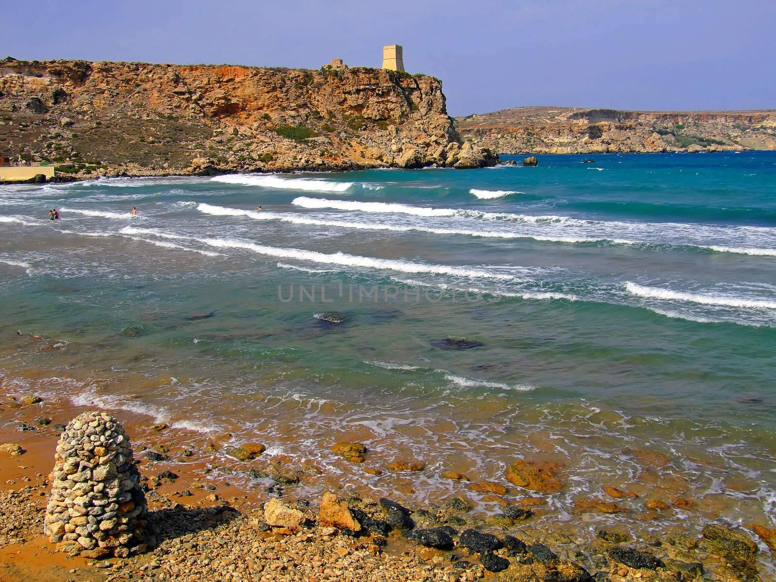 Clear blue Mediterranean waters on windy day, with beach and typical rocky coastline