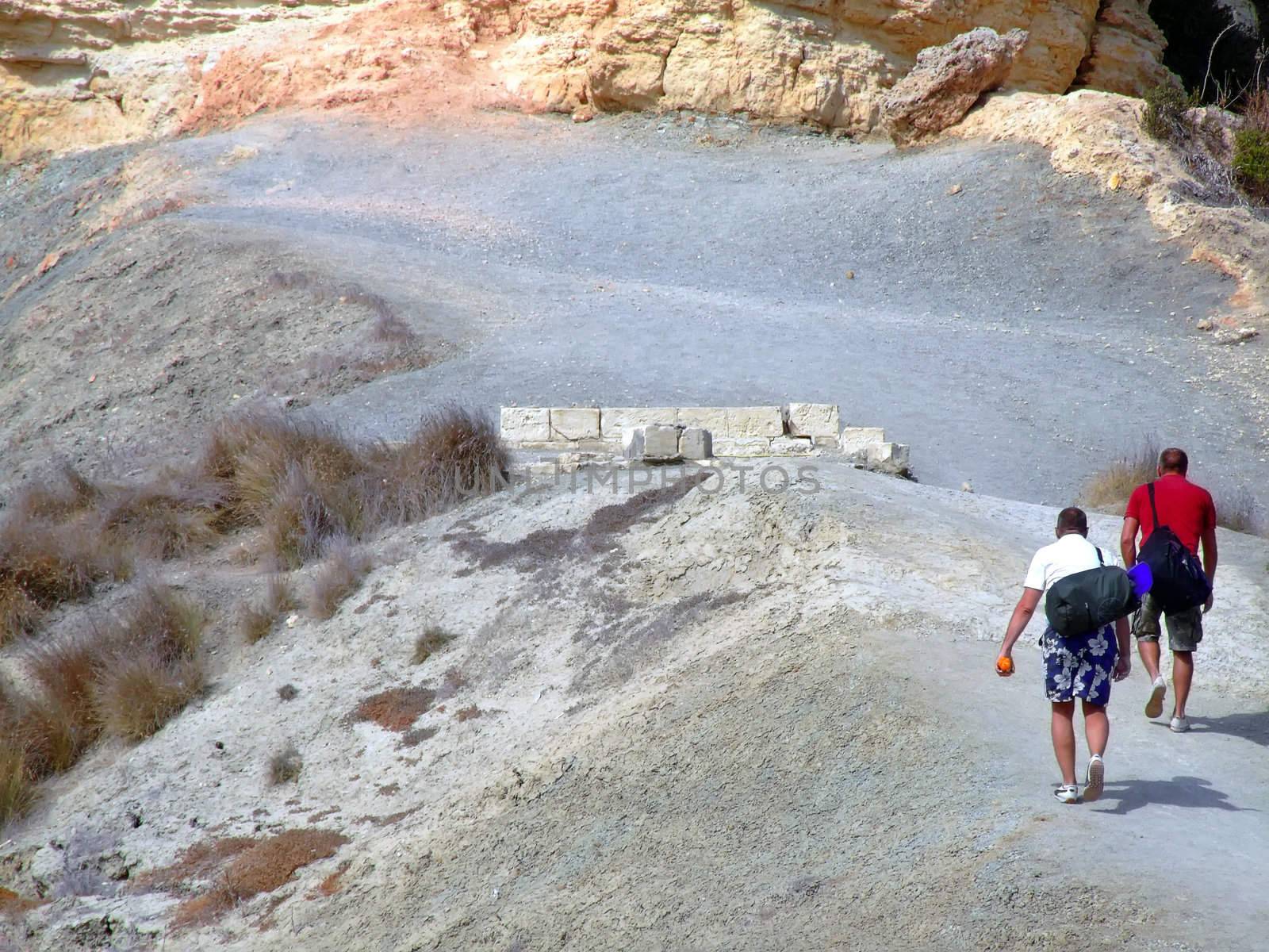 Adventure duo climbing up trek to Roman period ruins on top of clay slopes in Malta 