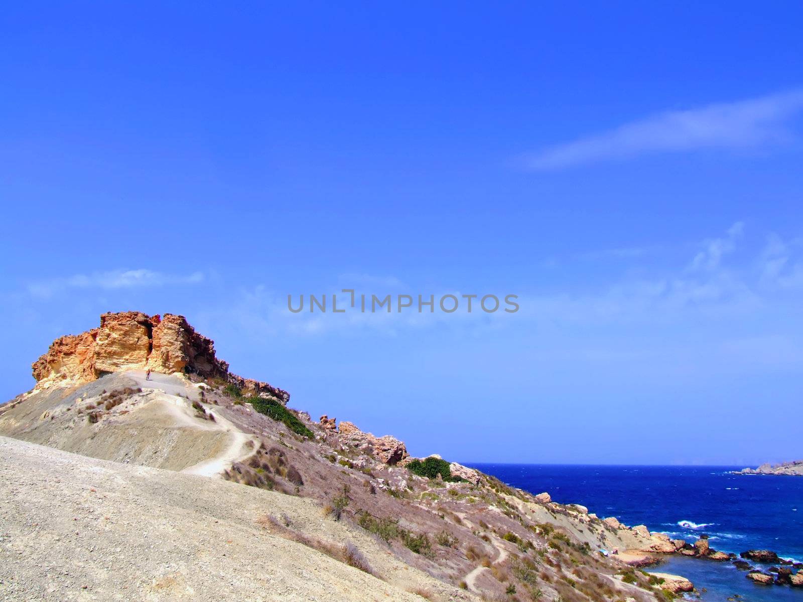 Clear blue Mediterranean waters on windy day, with beach and typical rocky coastline