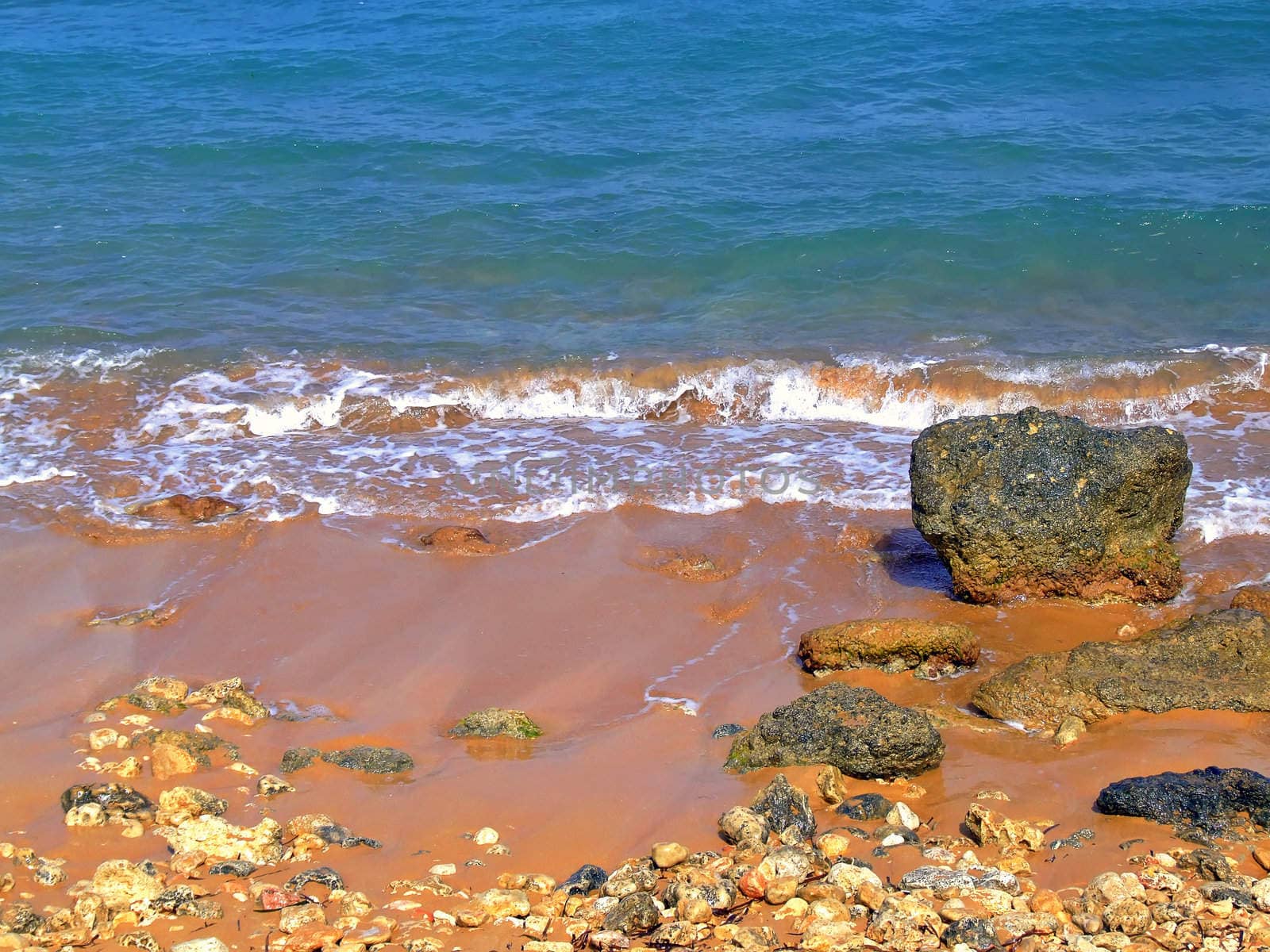 Clear blue Mediterranean waters on windy day, with beach and typical rocky coastline