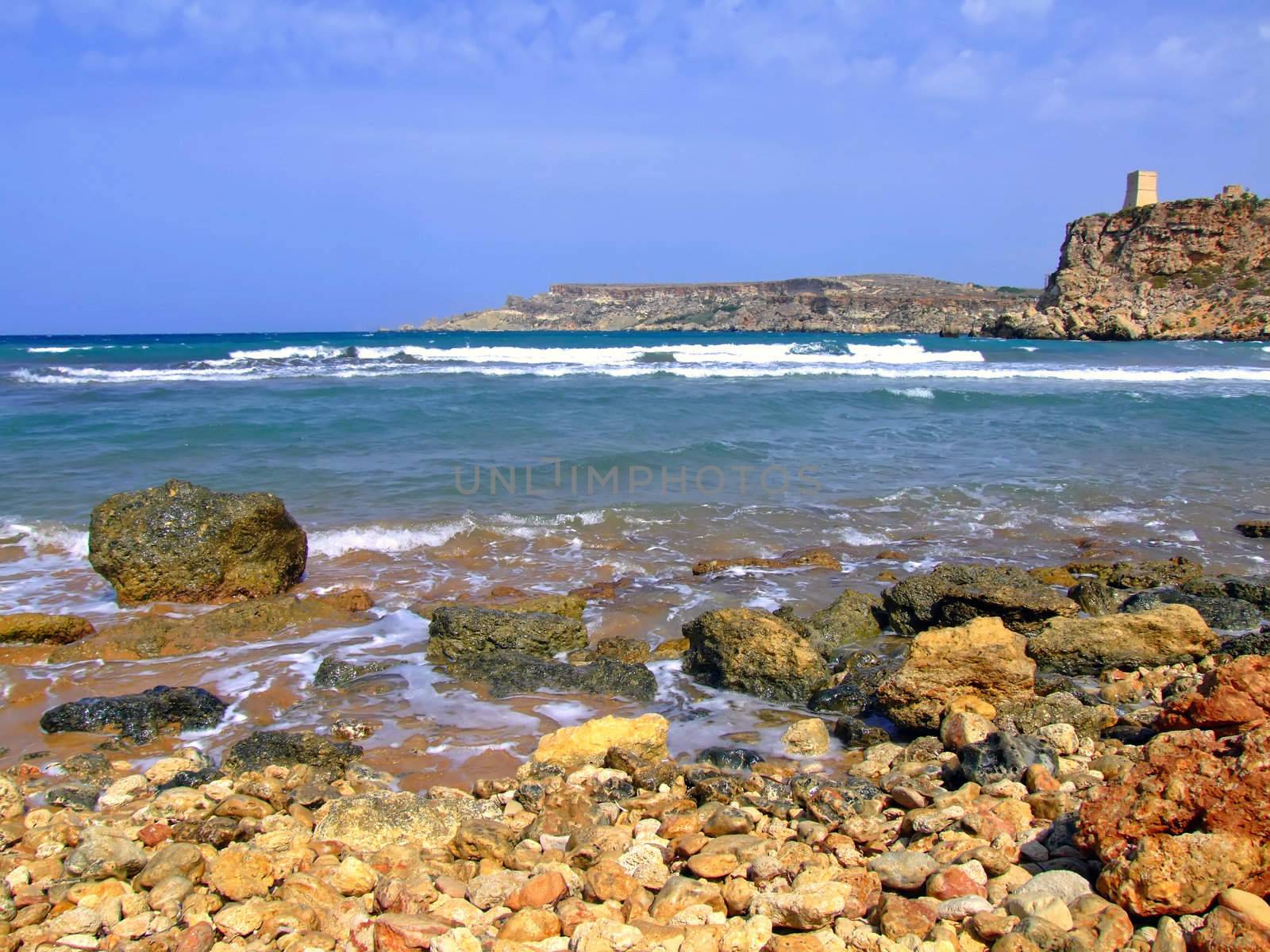 Clear blue Mediterranean waters on windy day, with beach and typical rocky coastline