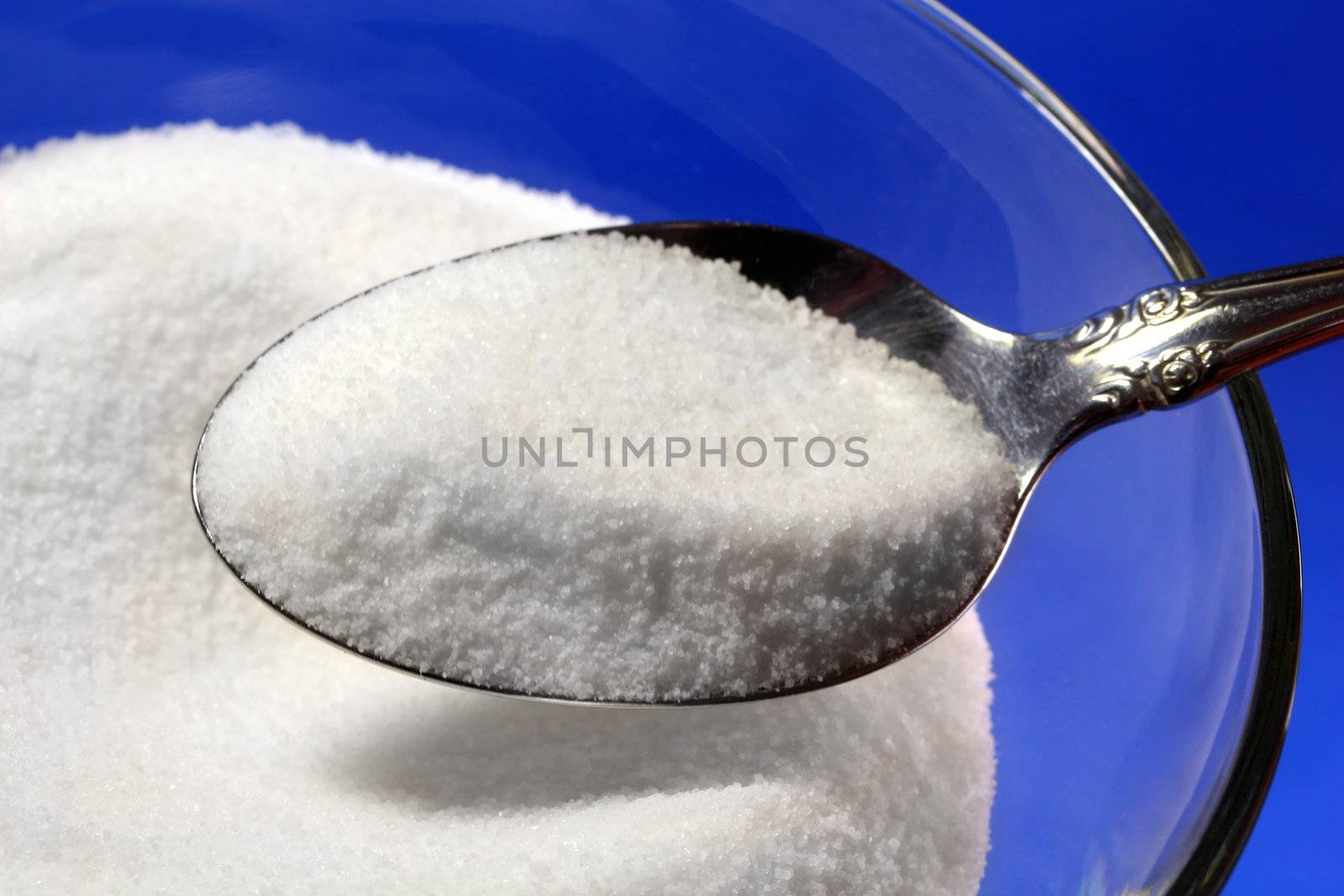 Spoonful of sugar on blue background.