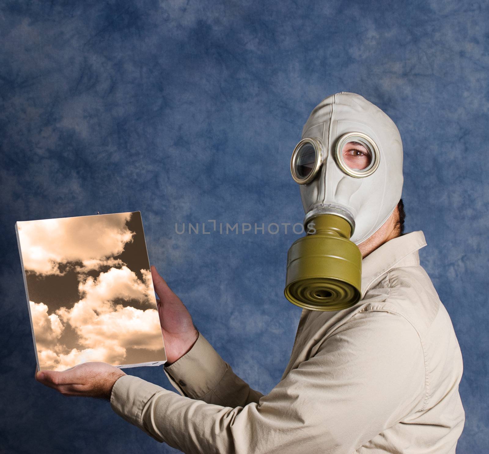 A man wearing a gas mask and holding a painting of a sky he painted