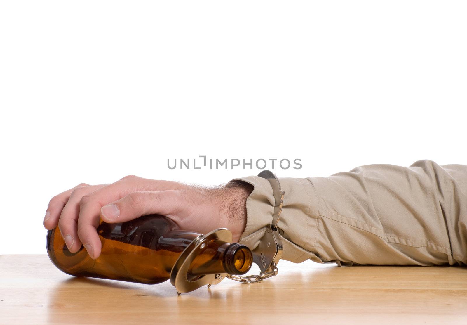 A mans hand is handcuffed to a bottle of beer,  with white copyspace above