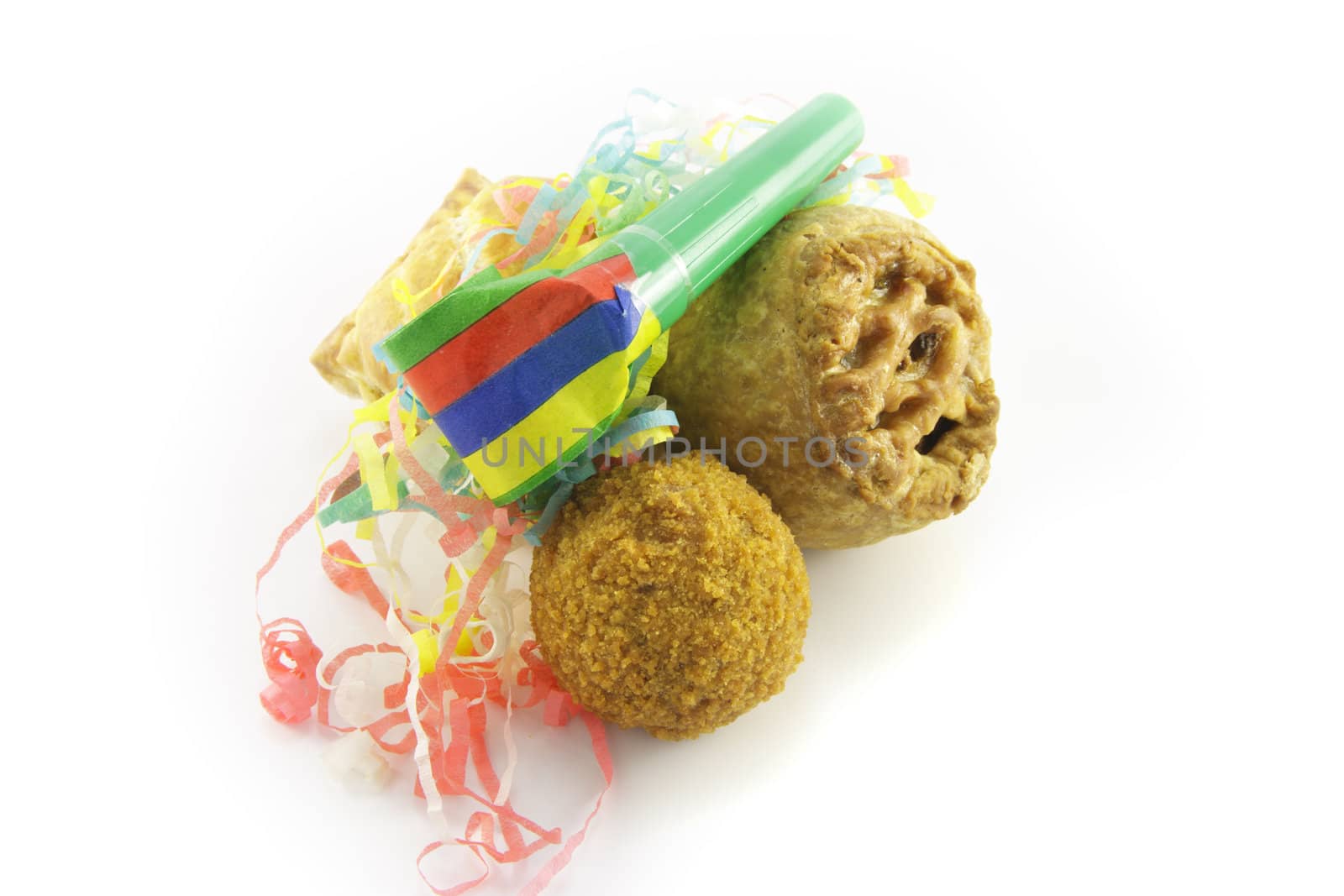 Small tasty pork pie, small round scotch egg and streamers with party blower on a reflective white background