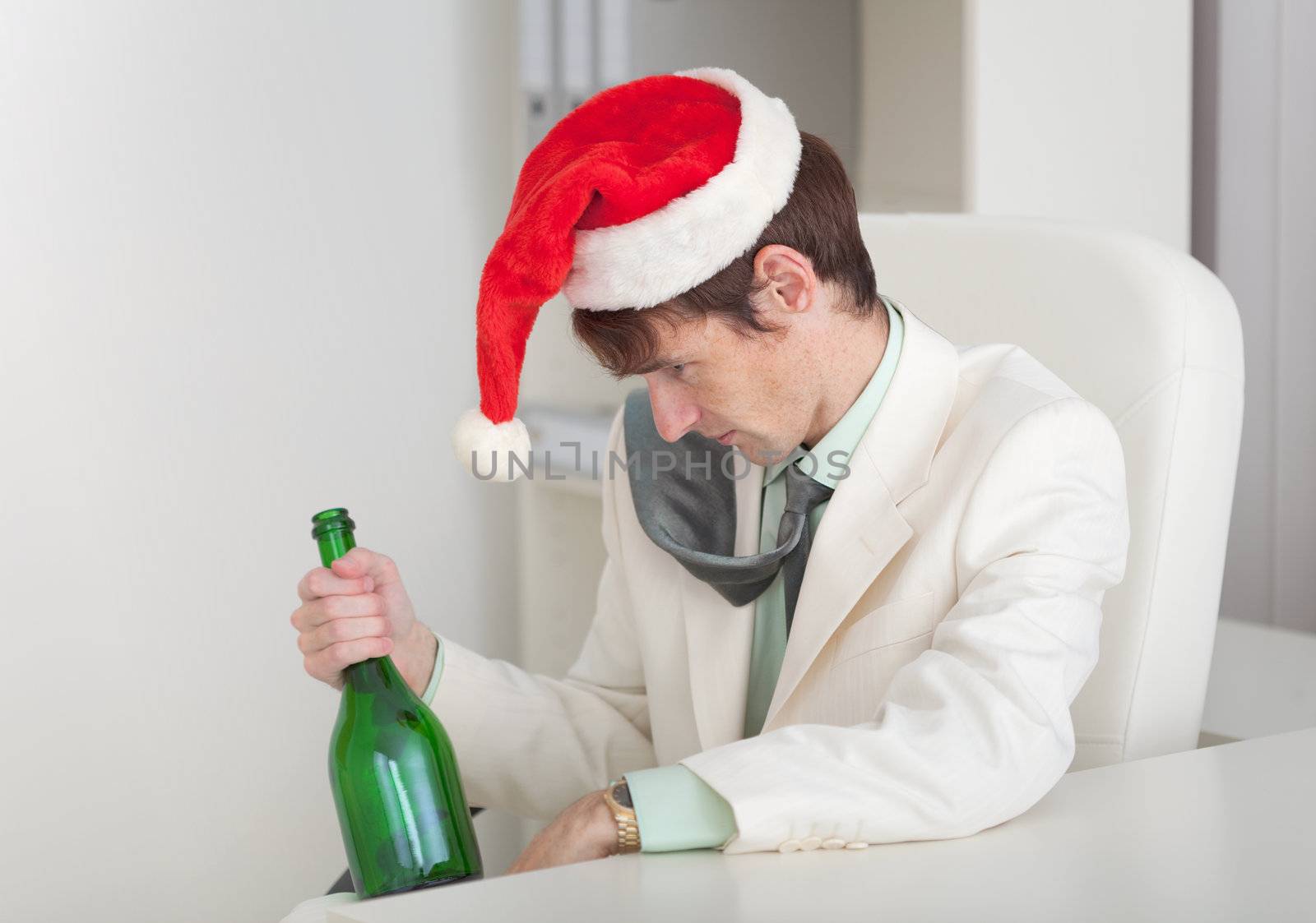 The drunken man in a Christmas cap with a bottle in a hand