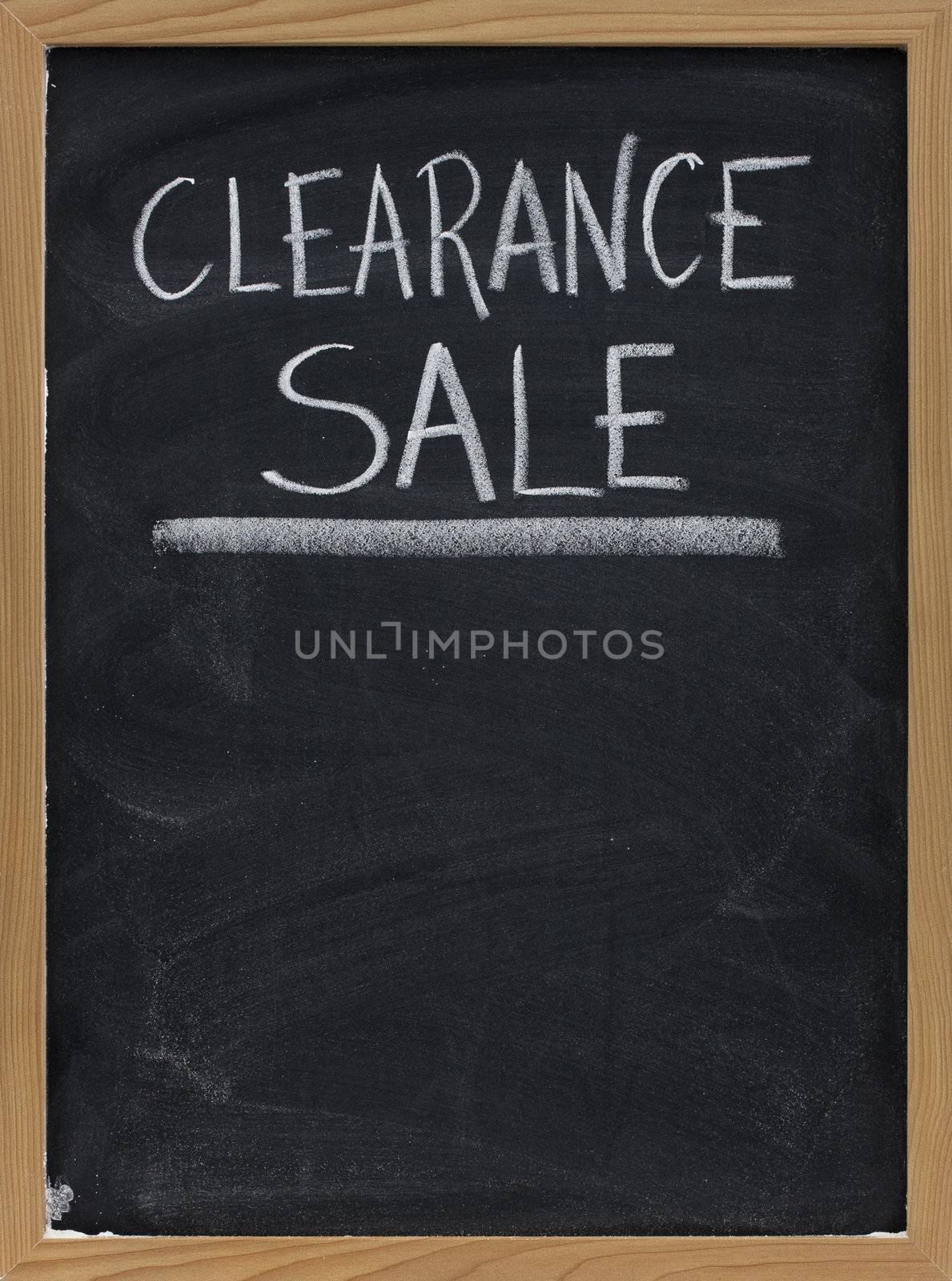 clearance sale text handwritten with white chalk on blackboard with copy space below