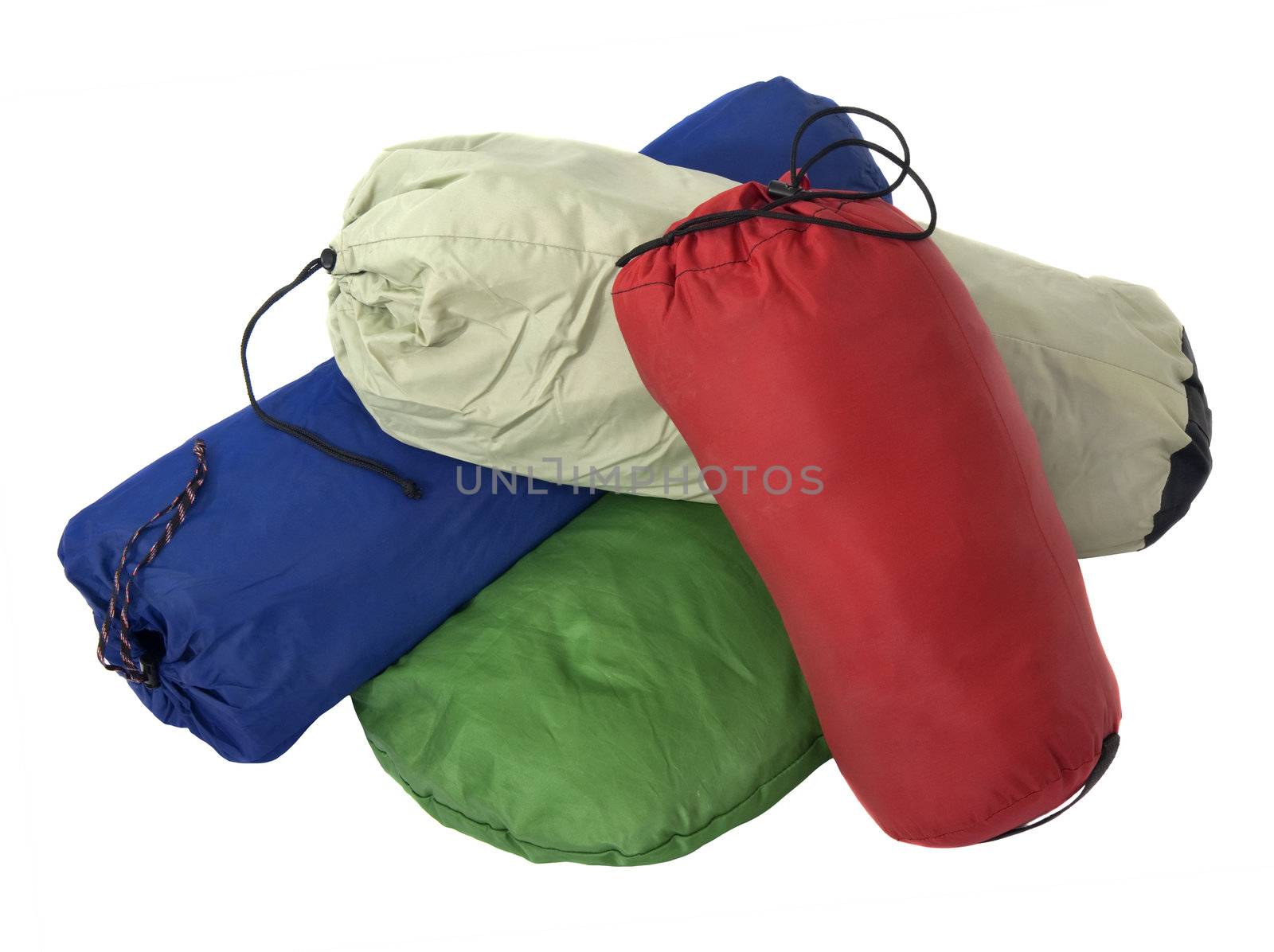 a pile of colorful bags with camping equipment (tent, sleeping bag, pad) isolated on white