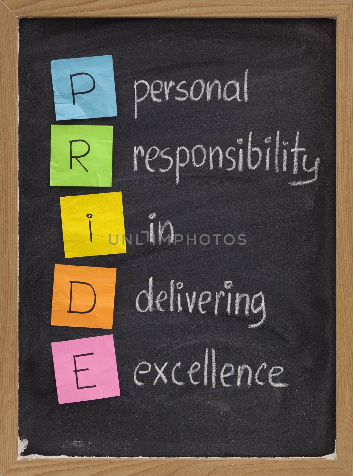 PRIDE (personal responsibility in delivering excellence) concept on blackboard, color sticky notes and white chalk handwriting