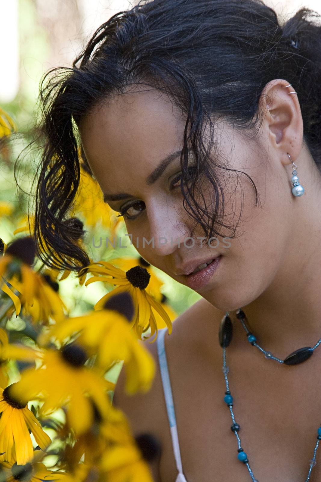 Twenty something columbian women smelling daisies in a garden