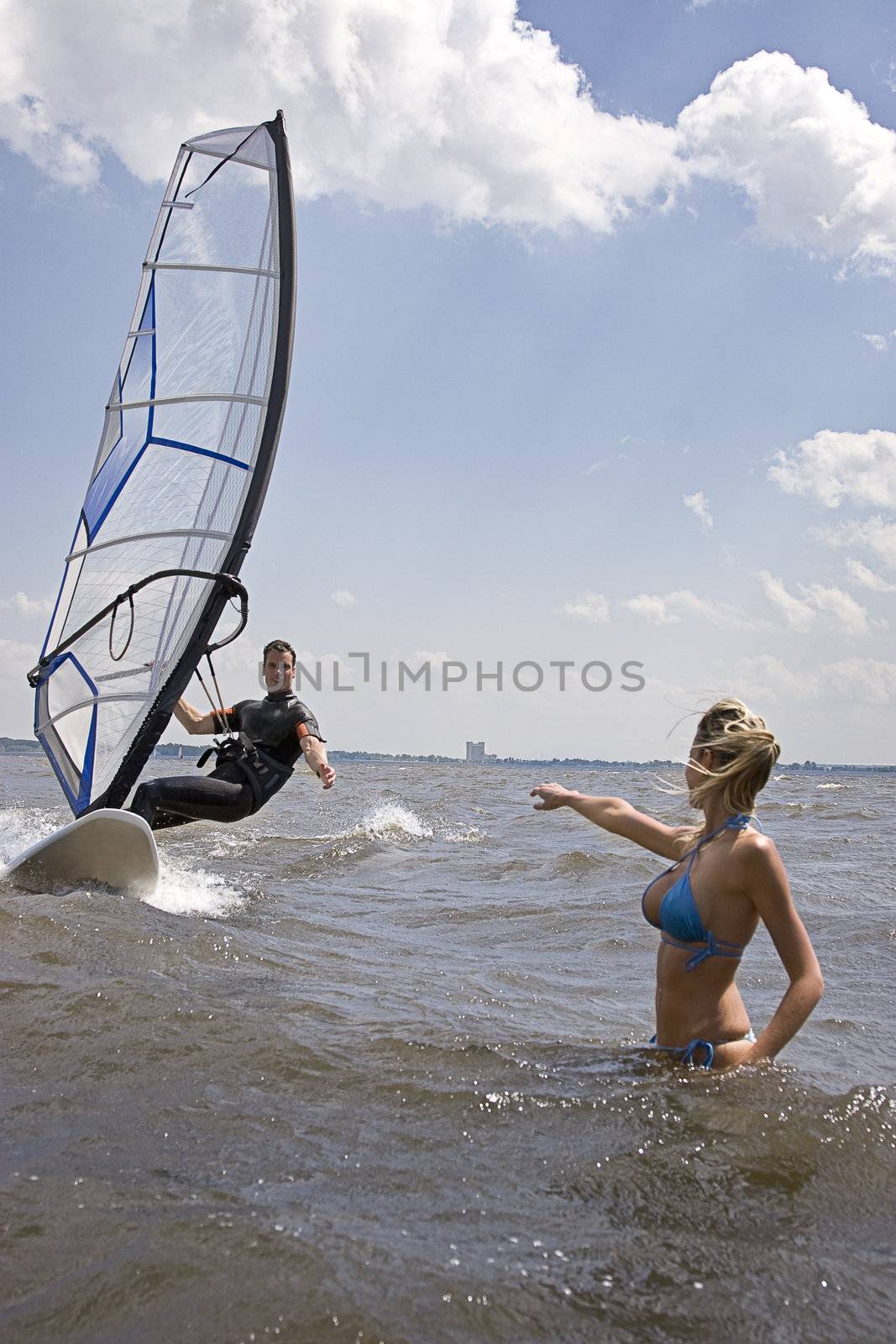 Windsurfer coming in at full speed with hand reaching for girlfriend