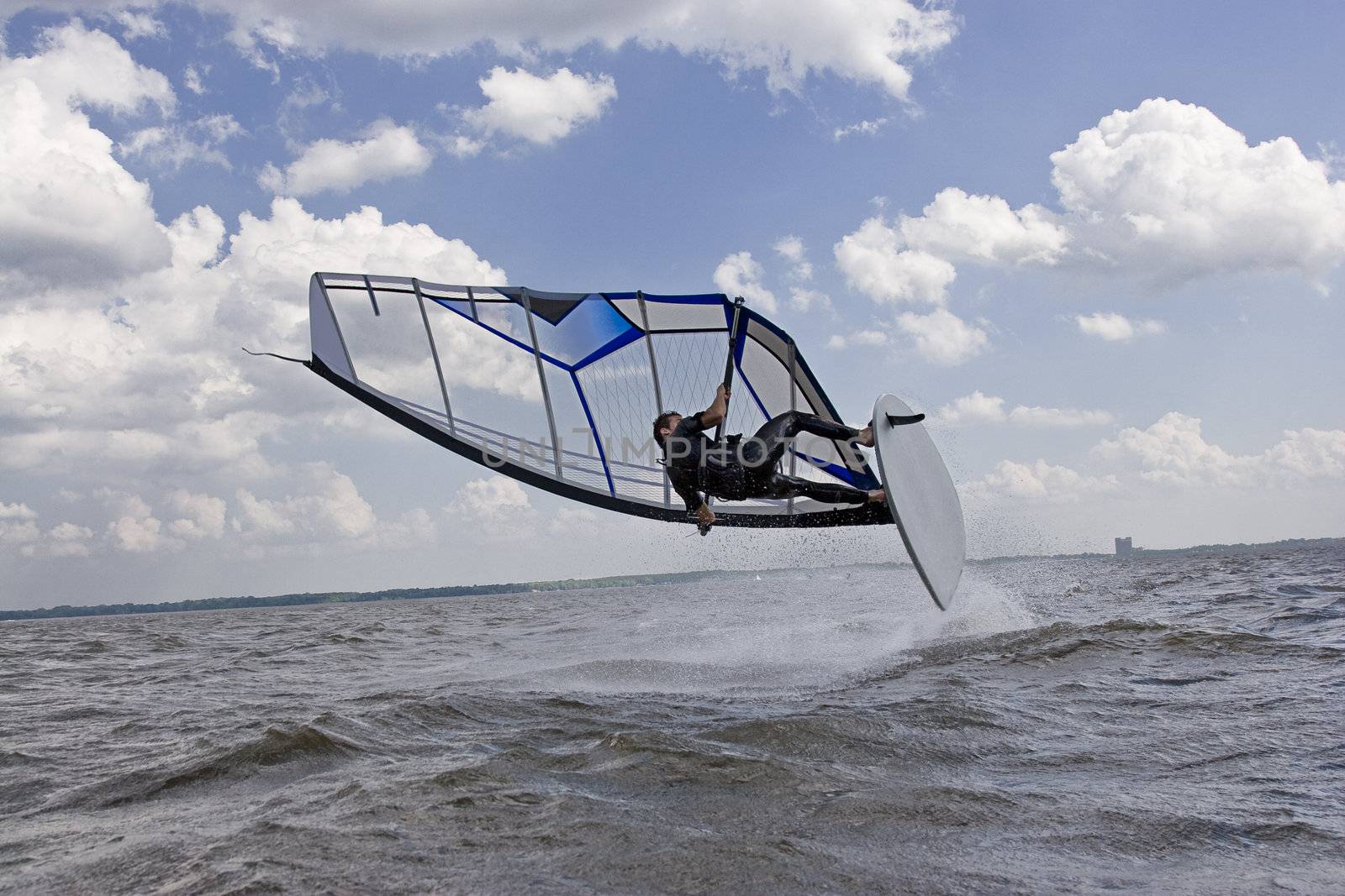 Windsurfer doing a jump trick in the water and to crash