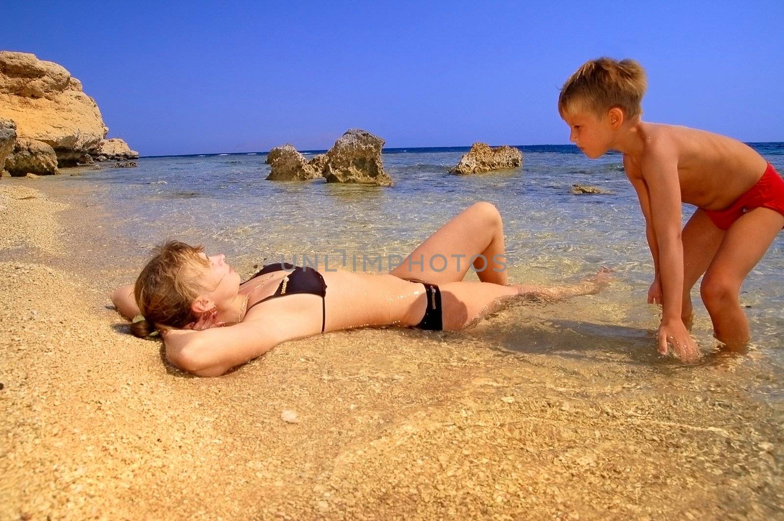 ma and son playing on beach on background blue sky 