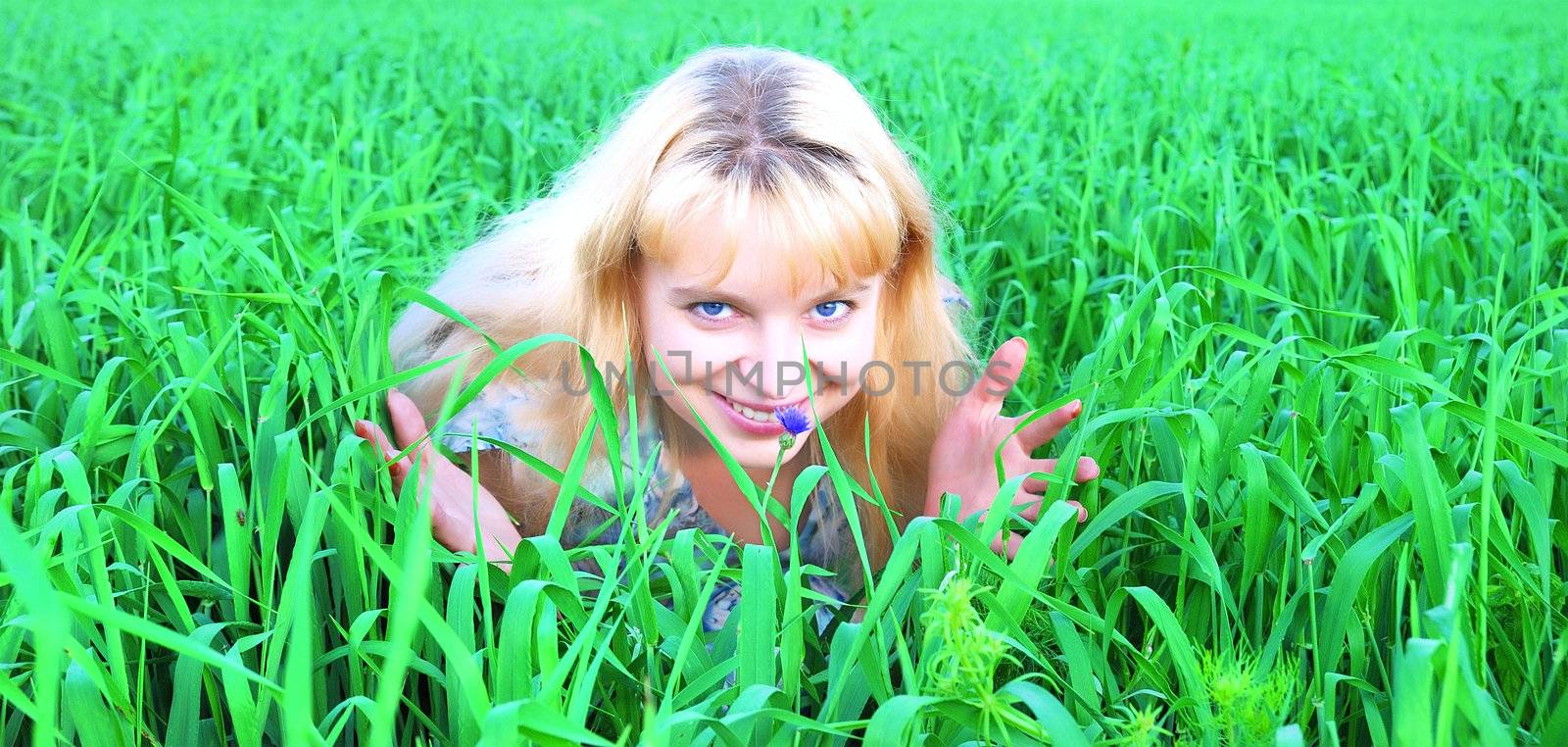 Girl sitting in a meadow enjoying the sun and smelling the flower