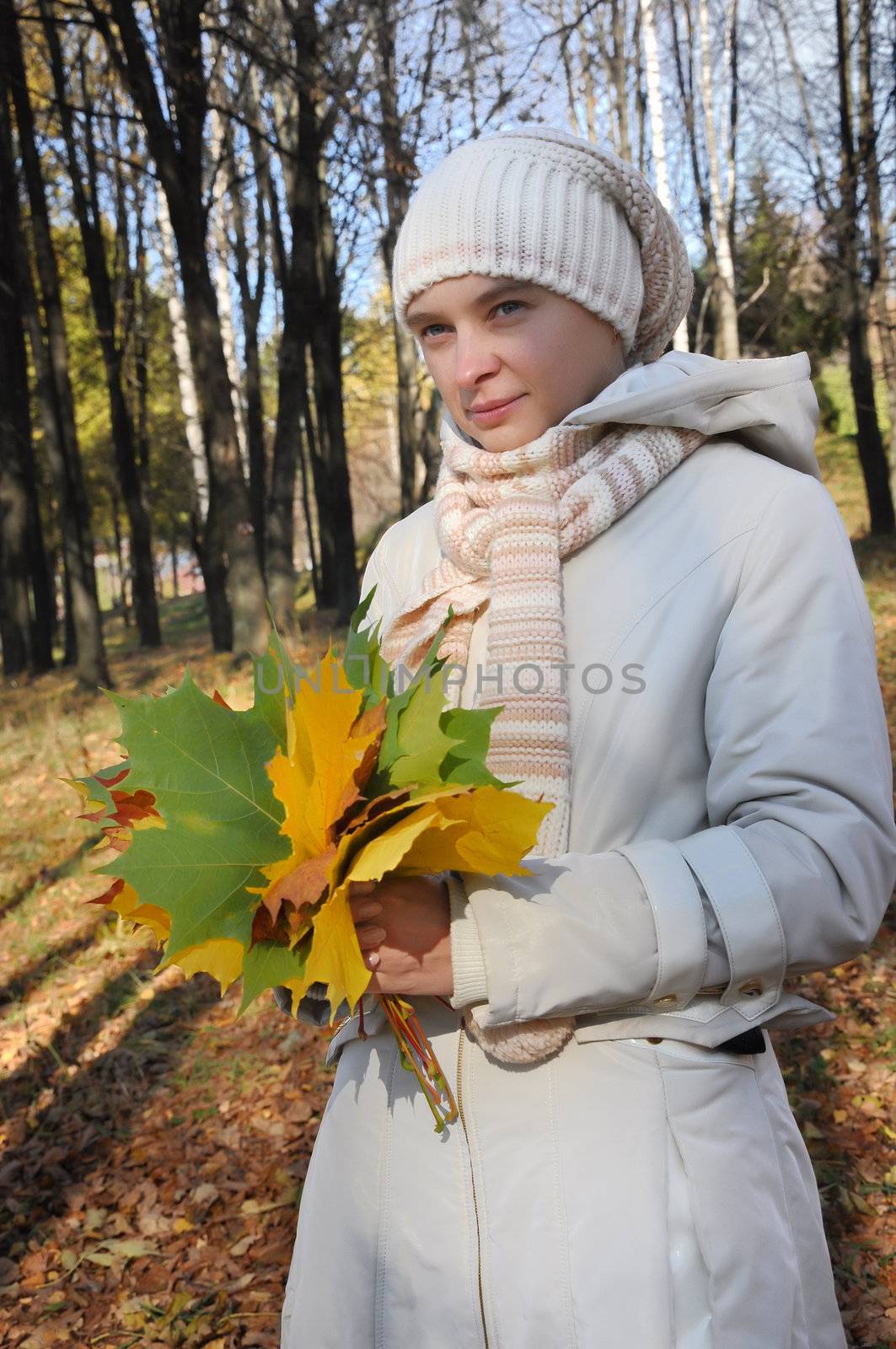romantic girl in an autumn wood with bouquet by maple leafs