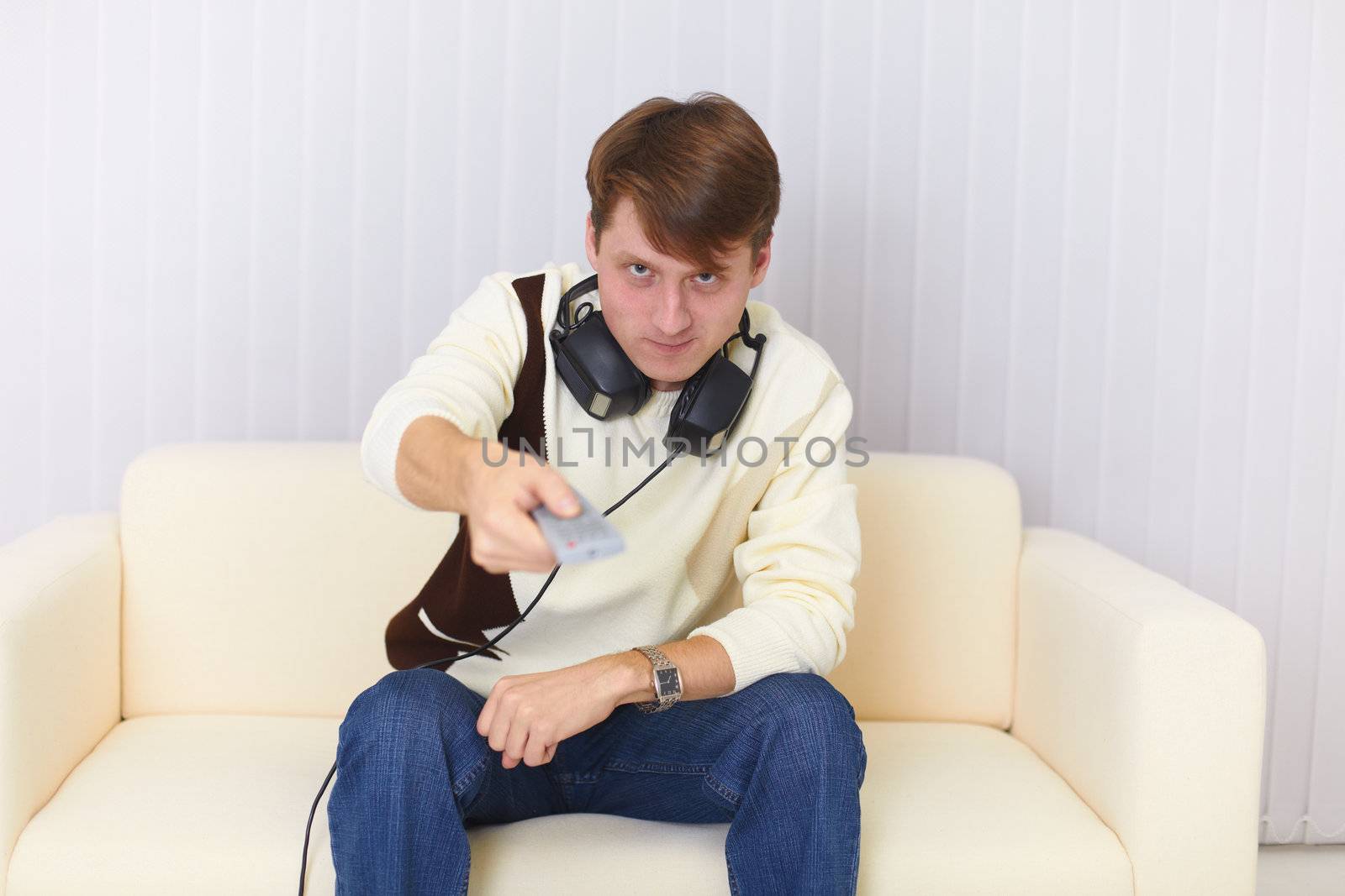 Man sits on sofa with earphones and remote control by pzaxe