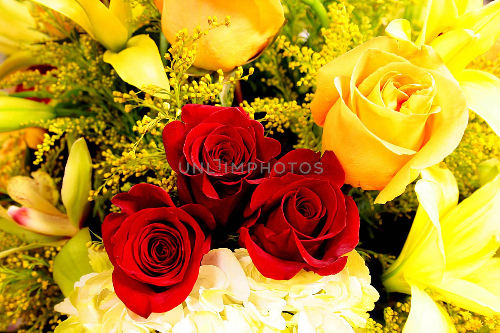 Darkly red three roses in the centre of a bouquet consisting of yellow colours.