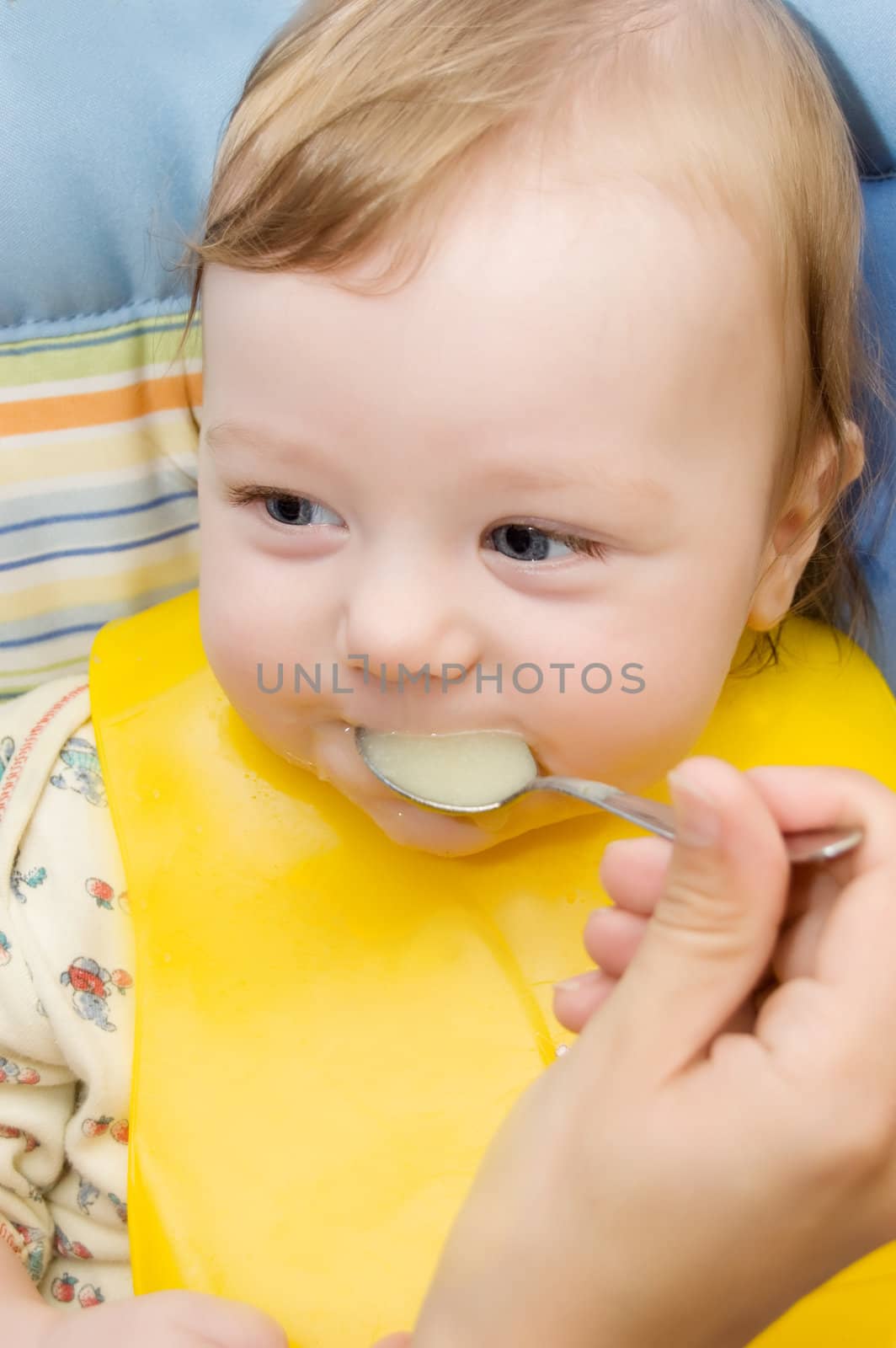 Mother's hand feeding baby boy with spoon