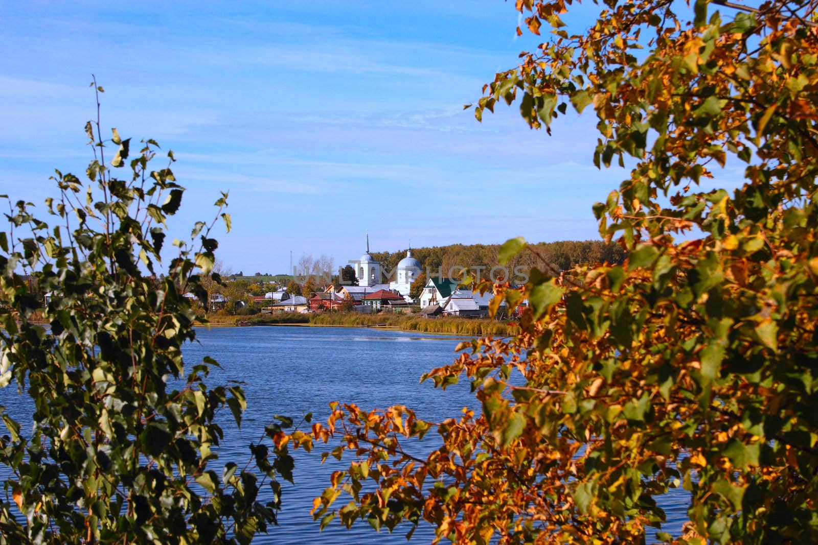 Autumn lake with a kind on village removed through vegetation