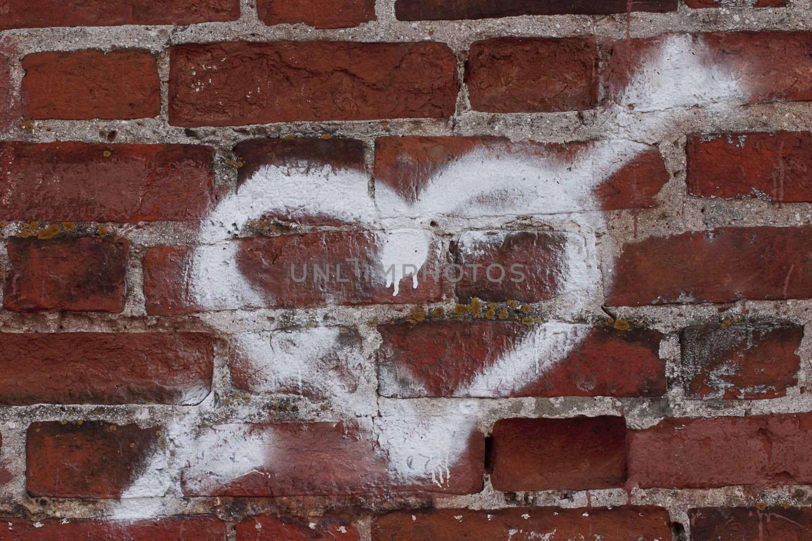 Heart pierced with an arrow drawn on red bricks
