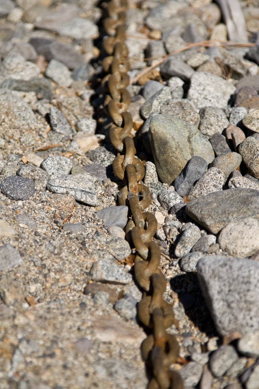 Close up of rusty anchor chain on rocky beach