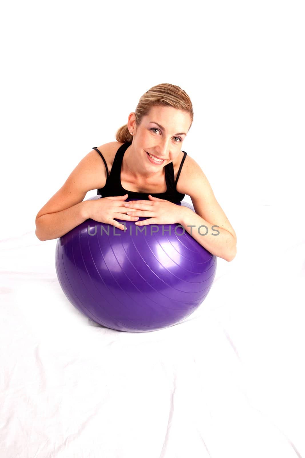 Smiling young lady relaxing on yoga ball