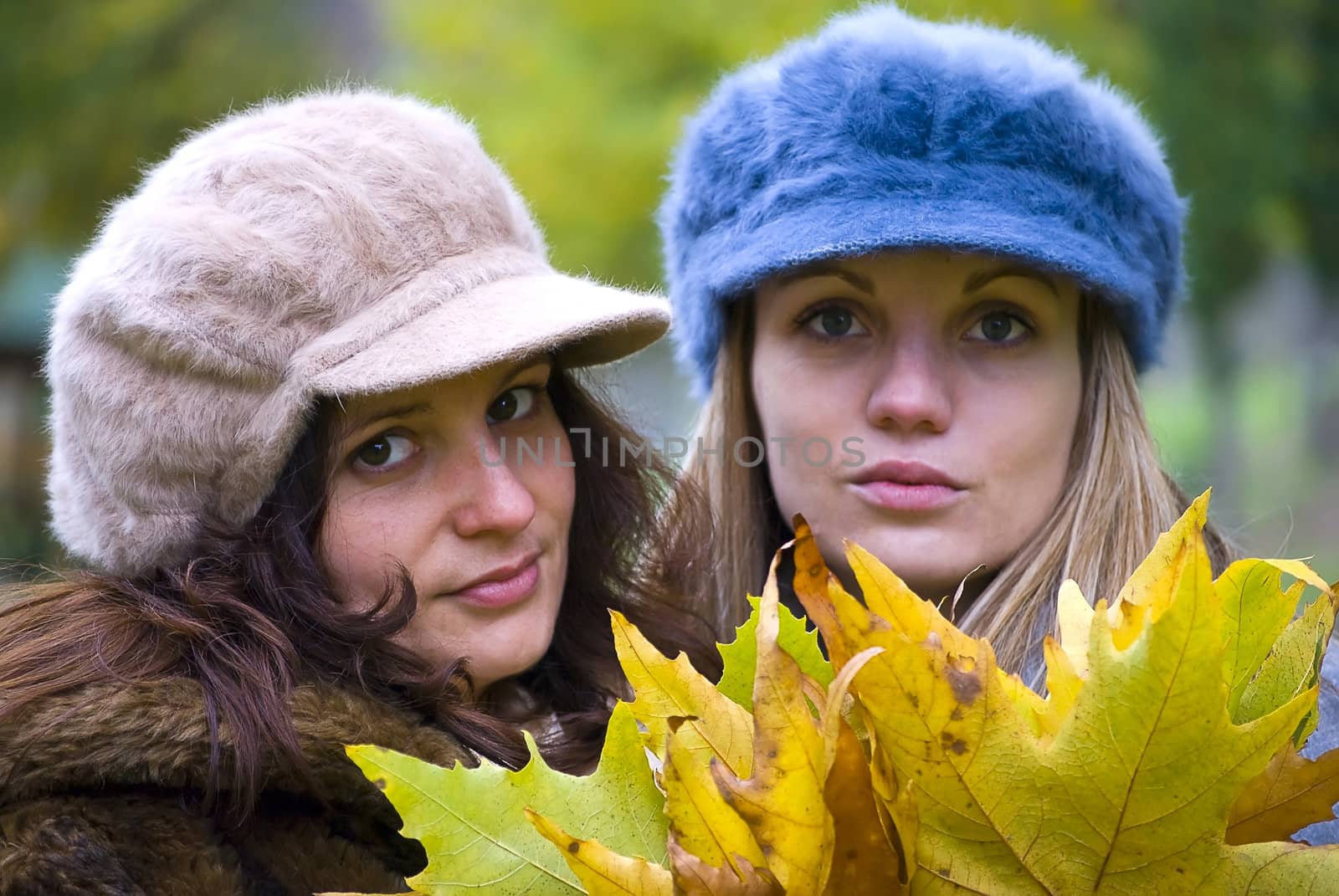two cute girls holding colorful autumn leaves 